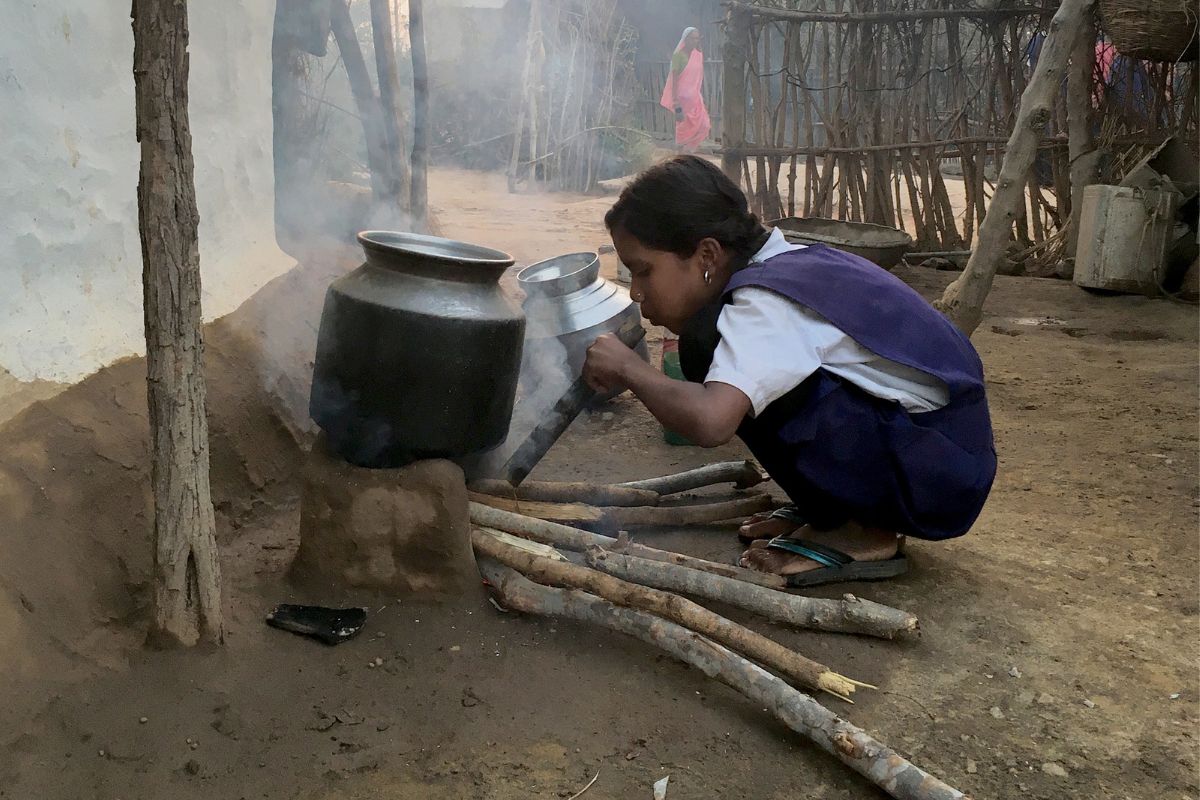 A woman uses the water heater and the fuel (crop residue) is seen in the background. Photo: Tamanna Ahmad/WCT