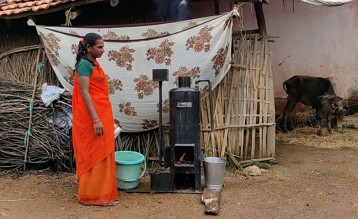 A woman uses the water heater and the fuel (crop residue) is seen in the background. Photo: Tamanna Ahmad/WCT